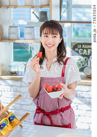 キッチンでイチゴをつまみ食いする女性の写真素材