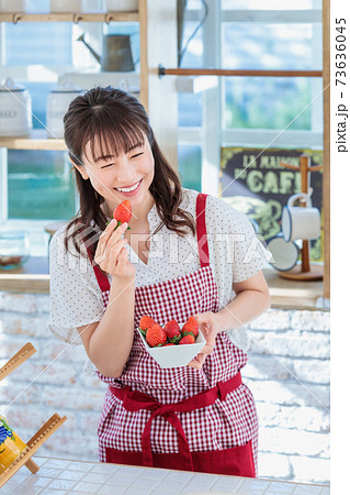 キッチンでイチゴをつまみ食いする女性の写真素材