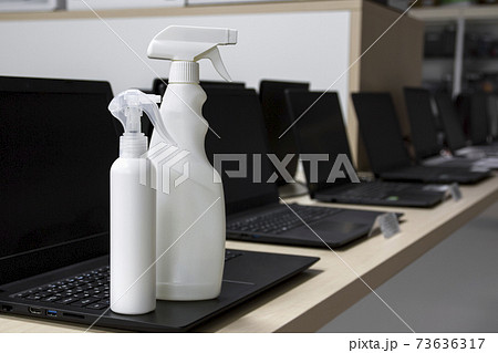 Disinfectant bottles against the background of the interior of a computer store. Protection from bacteria and viruses. Disinfectant bottles against the background of the interior of a computer store. Protection from bacteria and viruses. 73636317