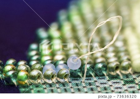 Embroiders with colorful beads. Close-up Embroiders with colorful beads. Close-up 73636320