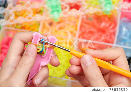 Rubber Band Weaving. Knitting rubber bands with loom knit. Hands of girl weaving wristband of rubber bands. Rubber Band Weaving. Knitting rubber bands with loom knit. Hands of girl weaving wristband of rubber bands. 73636339