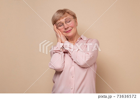 Mature woman sleeping tired dreaming and posing with hands together with closed eyes. Mature woman sleeping tired dreaming and posing with hands together with closed eyes. 73636572