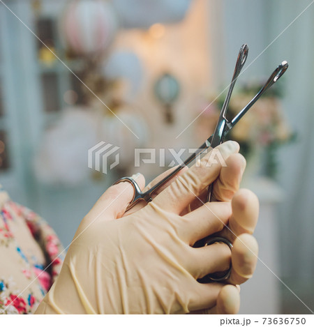 Doctor's hand in gloves and holding forceps. 73636750