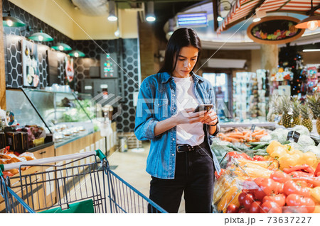 Young brunette woman looking at mobile phone 73637227
