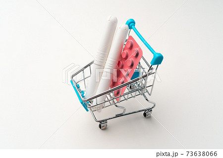 Female tampons and painkiller pills in toy shopping cart 73638066