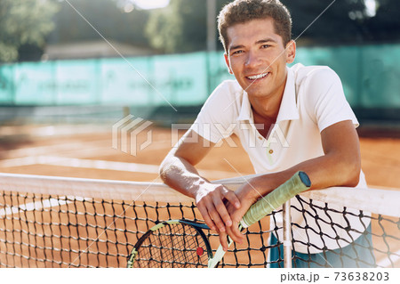 Young mixed race man tennis player with racket standing on tennis court Young mixed race man tennis player with racket standing on tennis court 73638203