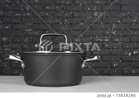 One new black cooking pot on white table One new black cooking pot on white table 73638260