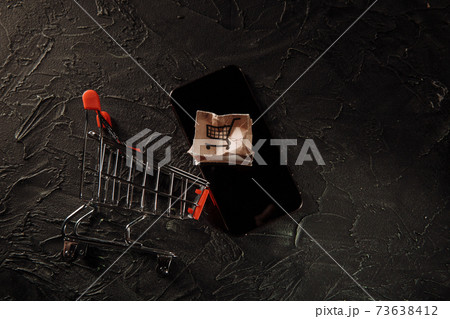Damaged paper box on a screen of smartphone and shopping cart. Online shopping, service and delivery concept Damaged paper box on a screen of smartphone and shopping cart. Online shopping, service and delivery concept 73638412