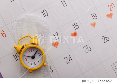 Female's menstrual cycle concept. Menstrual calendar with sanitary pad and alarm clock close-up Female's menstrual cycle concept. Menstrual calendar with sanitary pad and alarm clock close-up 73638571