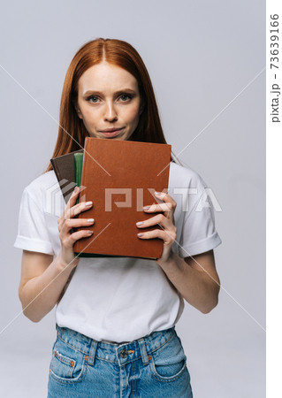 Upset sad young woman college student holding book and looking at camera on isolated background. 73639166
