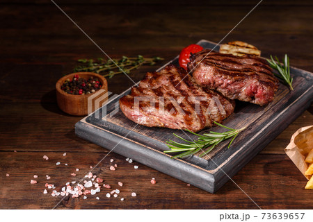 Fresh juicy delicious beef steak on a dark background Fresh juicy delicious beef steak on a dark background 73639657