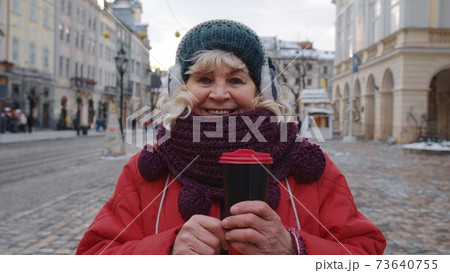 Portrait of senior woman tourist smiling, looking at camera in winter city center of Lviv, Ukraine Portrait of senior woman tourist smiling, looking at camera in winter city center of Lviv, Ukraine 73640755