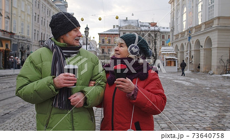 Senior old couple tourists grandmother grandfather traveling, drinking hot drink tea in city center Senior old couple tourists grandmother grandfather traveling, drinking hot drink tea in city center 73640758