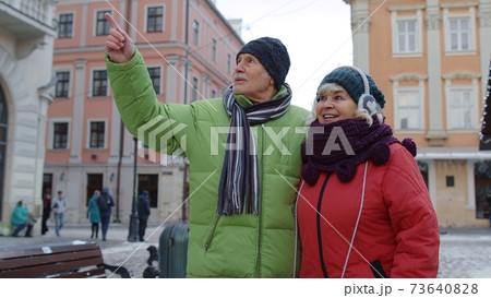 Stylish happy senior couple tourists grandmother grandfather walking, traveling in witer city center Stylish happy senior couple tourists grandmother grandfather walking, traveling in witer city center 73640828