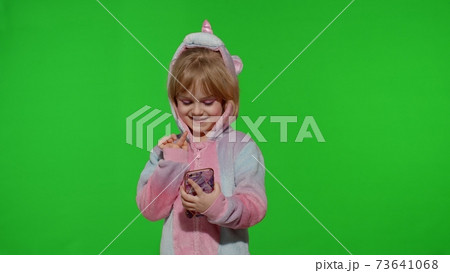 Excited little child girl in unicorn pajamas using mobile cell phone, found out great big win news Excited little child girl in unicorn pajamas using mobile cell phone, found out great big win news 73641068