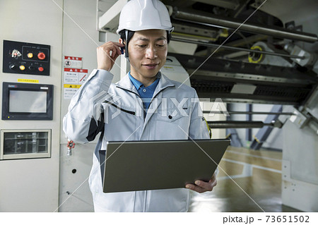 大型印刷機の前でリモート会議をする作業員男性 大型印刷機の前でリモート会議をする作業員男性 73651502