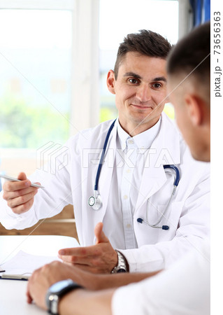 Smiling handsome doctor discuss problem with sad patient Smiling handsome doctor discuss problem with sad patient 73656363
