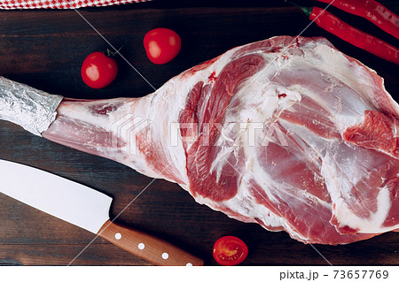 Raw lamb leg on dark wooden board 73657769