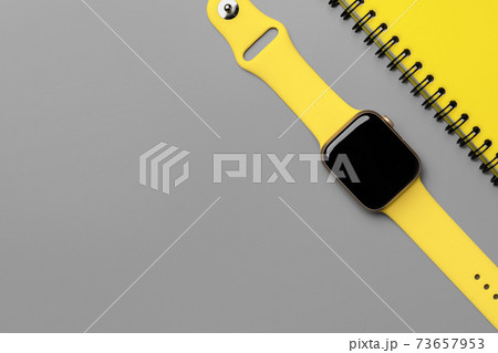 Yellow natepad and smart watch on gray background top view Yellow natepad and smart watch on gray background top view 73657953