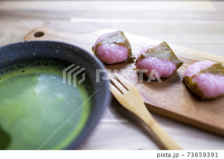 お抹茶とウッドプレートに盛り付けられた桜餅 73659391