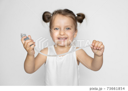 Cute little girl with blonde hair, happy to have her nose healthy and clean, posing to camera with cheerful smile, holding in hands nasal aspirator cleaner. Focus on nasal aspiration cleaner Cute little girl with blonde hair, happy to have her nose healthy and clean, posing to camera with cheerful smile, holding in hands nasal aspirator cleaner. Focus on nasal aspiration cleaner 73661854