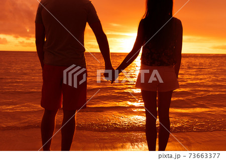 Couple silhouette holding hands at beach sunset Couple silhouette holding hands at beach sunset 73663377