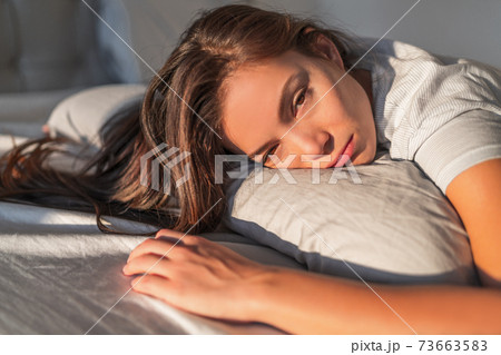Funny tired lazy asian young woman waking up in bed sleepy morning fatigue with half open eyes can't wake up lying on pillow in bed Funny tired lazy asian young woman waking up in bed sleepy morning fatigue with half open eyes can't wake up lying on pillow in bed 73663583