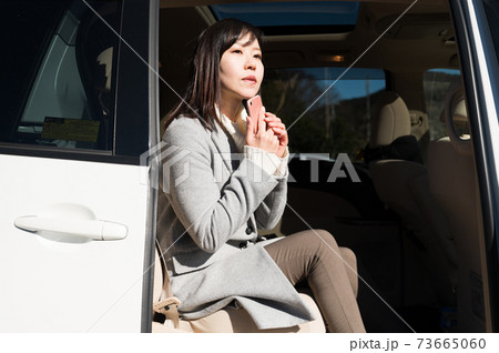 車のドアを開けて周りの様子を伺う女性の写真素材
