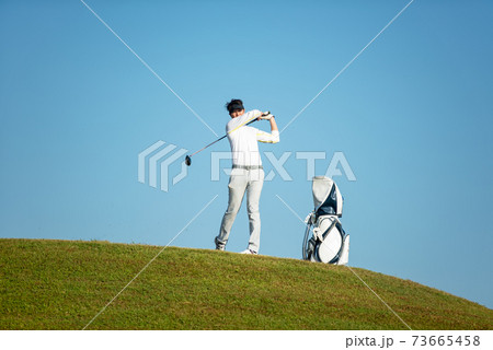 Golfer asia man approach on tee off for swing and hitting golf ball on slope green and looking fairway 73665458