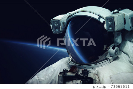 Astronaut at spacewalk. Cosmic art, science fiction wallpaper. Reflection in spacesuit vizor. Billions of galaxies in the universe. Elements of this image furnished by NASA 73665611