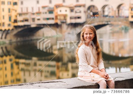 a little girl on the background of the Ponte Vecchio bridge in Florence.Family walk of the family in Italy.Tuscany 73666786