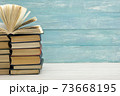 Composition with vintage old hardback books, diary, fanned pages on wooden deck table and red background. Books stacking. Back to school. Copy Space. Education background. 73668195