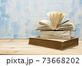 Composition with vintage old hardback books, diary, fanned pages on wooden deck table and red background. Books stacking. Back to school. Copy Space. Education background. 73668202