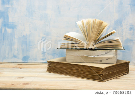 Composition with vintage old hardback books, diary, fanned pages on wooden deck table and red background. Books stacking. Back to school. Copy Space. Education background. Composition with vintage old hardback books, diary, fanned pages on wooden deck table and red background. Books stacking. Back to school. Copy Space. Education background. 73668202