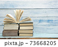 Composition with vintage old hardback books, diary, fanned pages on wooden deck table and red background. Books stacking. Back to school. Copy Space. Education background. 73668205