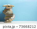 Composition with vintage old hardback books, diary, fanned pages on wooden deck table and red background. Books stacking. Back to school. Copy Space. Education background. 73668212