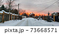 Photo of an evening street with a fence and houses in the rays of the sunset 73668571