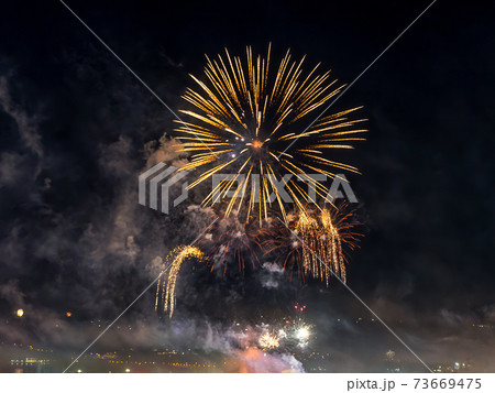 Bright fireworks sparkle in the dark sky. The small town celebrates with colorful fireworks. 73669475