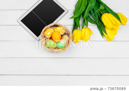 tablet screen for message and colorful tulips and easter eggs on wooden background tablet screen for message and colorful tulips and easter eggs on wooden background 73670089