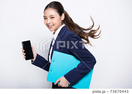 携帯電話とクリップボードをを持って走る仕草をしている女性 73670443