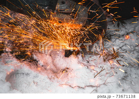 Bright sparks fly out of angle grinder, close up 73671138
