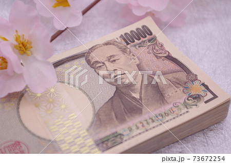 日本伝統文様のおしゃれな帯封が巻かれた札束に造花の桜を添えて　春の門出や記念日をイメージ 73672254