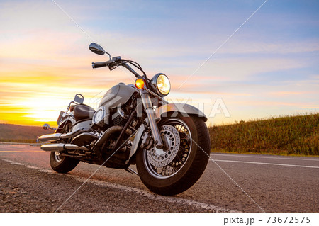 Classic motorcycle chopper, cruiser on empty asphalt road on sunset sky background 73672575