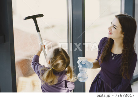Daughter and mother cleaning window together Daughter and mother cleaning window together 73673017