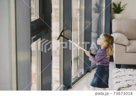 Little girl cleaning windows with vacuum cleaner Little girl cleaning windows with vacuum cleaner 73673018