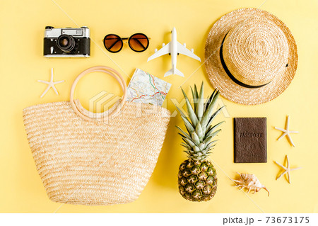 Woman's beach accessories: rattan bag, straw hat, retro camera, model plane, airplane on yellow background. The concept of travel. Summer background. 73673175