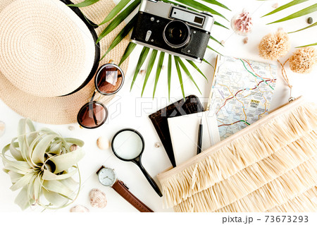 Traveler accessories on white background with retro camera, straw hat, bag, sunglasses, map and tropical palm leaf. 73673293