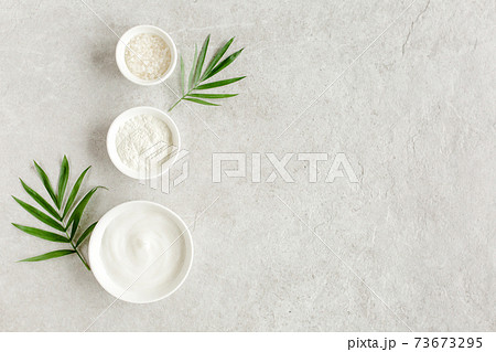 Female skin and body care cosmetic products set: facial cream, cosmetic clay, sea salt on gray marble background. Beauty blogger, salon treatments  73673295