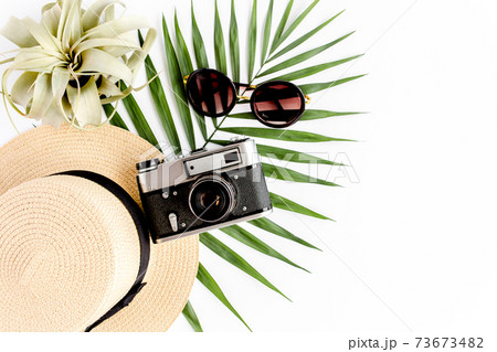 Flat lay traveler accessories on white background with retro camera, straw hat, sunglasses, and tropical palm leaf. Travel concept background. Flat lay traveler accessories on white background with retro camera, straw hat, sunglasses, and tropical palm leaf. Travel concept background. 73673482