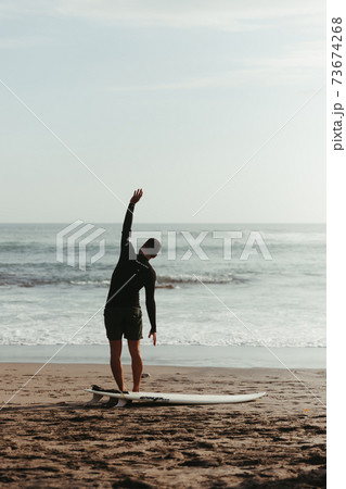 Surfer warming up. A person standing on a beach 73674268